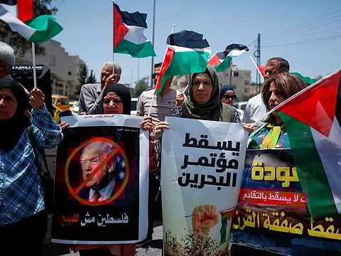 Palestinians hold banners and shout slogans as they rally against the US-led Israeli-Palestinian peace conference in Bahrain scheduled for next week