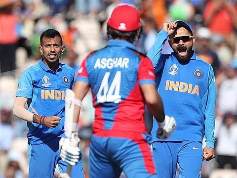 India's Yuzvendra Chahal, left, and captain Virat Kohli, right, celebrate the dismissal of Afghanistan's Asghar Afghan, centre, during their World Cup match at the Hampshire Bowl in Southampton, on Saturday, June 22, 2019.
