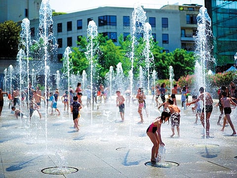 Children play at a fountain in a park on Thursday in Paris. Around France, some schools are closed because of high temperatures.