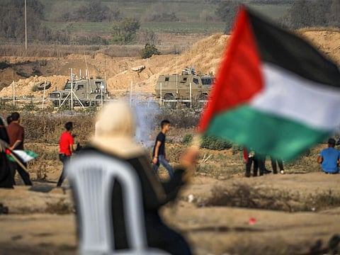 A woman waves a Palestinian flag while protesters demonstrate along the barbed-wire fence with Israel at the border near Bureij in the central Gaza Strip on June 28, 2019.