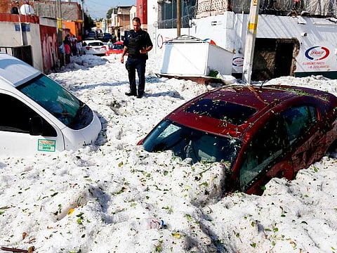 A policeman stands next to vehicles buried in hail in the eastern area of Guadalajara
