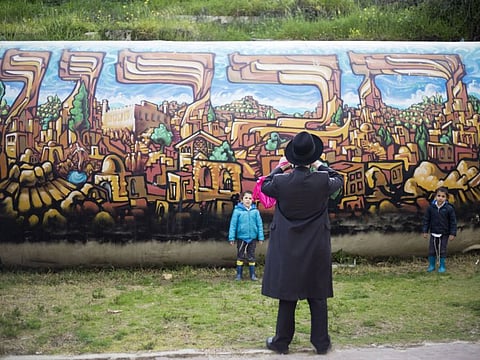 A jewish man takes a photo of his children in the Israeli-occupied part of the West Bank city of Hebron.