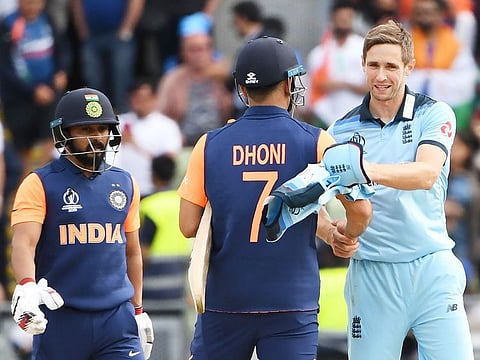 England's Chris Woakes (R) shakes hands with India's Mahendra Singh Dhoni (C) and Kedar Jadhav (L) after the match at Edgbaston in Birmingham.