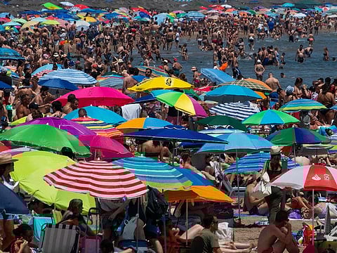 People swarm a public beach amid a heatwave in Valencia.  This 12-month average does not mean that the world has yet surpassed the 1.5°C (2.7°F) global warming threshold, which describes a temperature average over decades, beyond which scientists warn of more extreme and irreversible impacts.