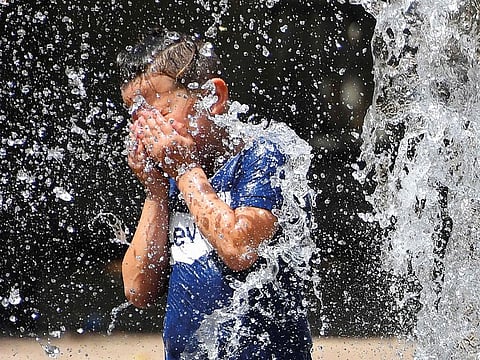 A child cools off under water jets in a fountain during a heatwave in Montpellier, southern France.