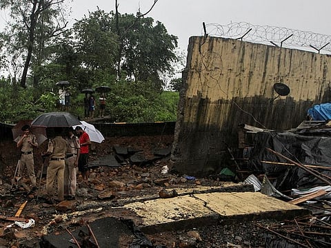 Police personnel stand among the debris after a wall collapsed on hutments due to heavy rains in Mumbai, India July 2, 2019.