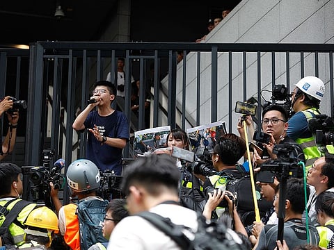 Joshua Wong, co-founder of the Demosisto political party, is surrounded by members of the media as he speaks in front of the police headquarters during a demonstration in Hong Kong, China.