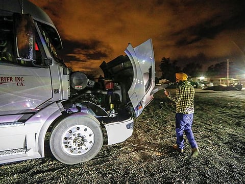 Palwinder Singh, in the darkness of early morning, checks his truck before getting on the road on a week-long trip to Indiana, delivering fresh produce from California.