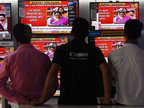 People watch Indian Finance Minister Nirmala Sitharaman delivering her budget speech on television screens at an electronics store in New Delhi on July 5, 2019.