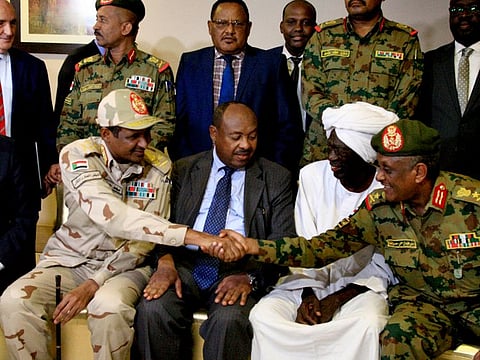 African union envoy to Sudan Mohamed al-Hacen Lebatt (L) sits next to Sudan's deputy chief of the ruling military council General Mohamed Hamdan Dagalo as he shakes hands with an army general following a press conference in Khartoum in which they announced ruling generals and protest leaders have reached an agreement on the disputed issue of a new governing body on July 5, 2019.