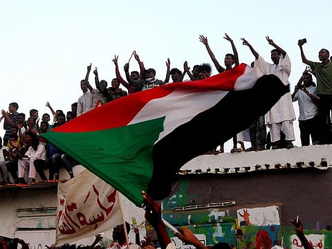 Sudanese people chant slogans and wave their national flag as they celebrate after Sudan's ruling military council and a coalition of opposition and protest groups reached an agreement to share power during a transition period leading to elections, along the streets of Khartoum on July 5, 2019.