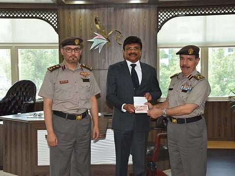 Brig Arif Al Shamsi presents the gold card to Lalu Samuel in the presence of Col Abdullah Saleh Al Naqbi.