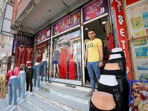 Syrian shopkeeper Mustafa poses in front of his clothes shop in Istanbul's Kucukcekmece district