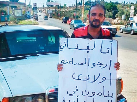Adel Al Hellani holds a placard, seeking help from the public to tide over the problem of unpaid rents.