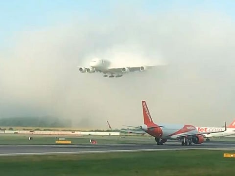 An Emirates A380 landing through a bed of low clouds.
