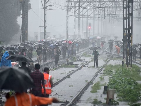 People cross a waterlogged railway track following heavy monsoon rain in Thane.
