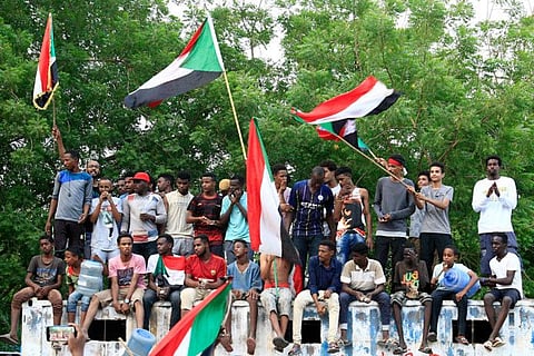Sudanese demonstraters wave their national flag as they celebrate in Khartoum early on August 3, 2019, after Sudan's ruling generals and protest leaders reached a "full agreement" on the constitutional declaration.