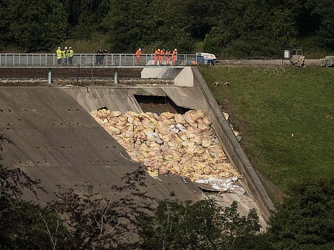 Engineers and members of the emergency services assess the damaged spillway of the Toddbrook Reservoir dam, the damamged section of which is filled with bags of aggregate to reinforce the structure, above the town of Whaley Bridge in northern England on August 4, 2019.