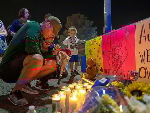 Rene Aguilar and Jackie Flores pray at the makeshift memorial for the victims of Saturday's mass shooting at a shopping complex in El Paso, Texas.