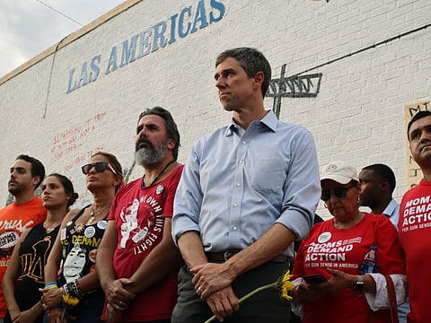 Muralist Manuel Oliver at center in red, is flanked by his wife and daughter, left, in black, and presidential candidate Beto O'Rourke, in blue, right, in El Paso, Aug. 4, 2019.