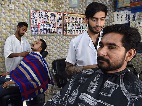 Barbers Mohammed Hussain and Omer Ul Satar, attending to customers at Al Raqam Wahid barber shop in Sharjah. Photo taken August 5, 2019.