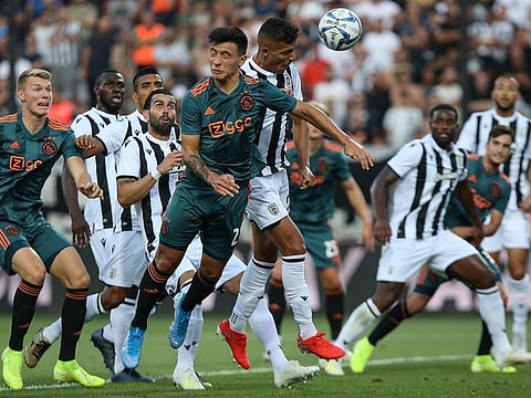 Ajax's Lisandro Martínez (center left) jumps for a header during the Champions League third qualifying round, first leg soccer match against PAOK FC, at Toumba Stadium in the northern Greek port city of Thessaloniki, on Tuesday.