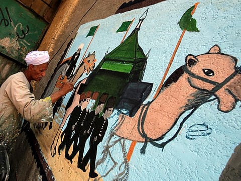 The artist Eid Al Salwaawi paints murals about the holy Kaaba and the rituals of the Hajj pilgrimage to Mecca, in Cairo, Egypt, July 17, 2019.