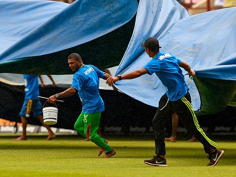 Ground staff pull rain covers during the 1st ODI match between West Indies and India at Guyana National Stadium in Providence, Guyana, on August 8, 2019.