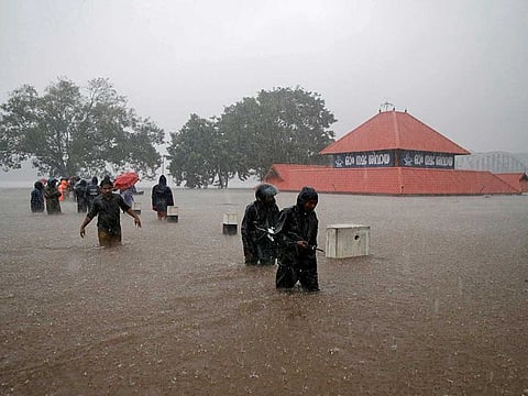 Members of a rescue team wade through a water-logged area past a submerged temple during heavy rains on the outskirts of Kochi in the southern state of Kerala