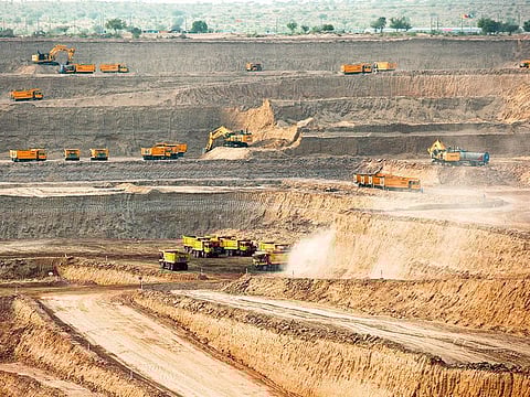 Excavators and dump trucks excavate sand and rocks from an open pit mine at the Sindh Engro Coal Mining Co. site in the Thar desert, Pakistan.