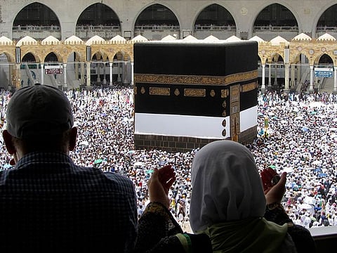 Muslim pilgrims pray as they watch thousands of pilgrims circumambulate around the Kaaba.