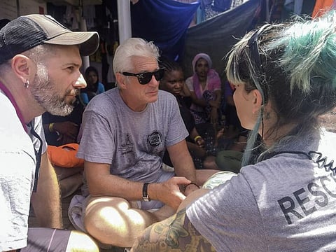 Actor Richard Gere, center, talks with staff members of the Open Arms Spanish humanitarian boat as it cruises in the Mediterranean Sea.