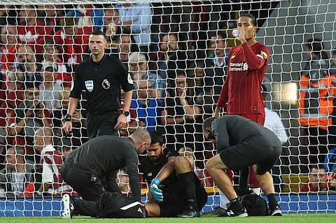Liverpool's Brazilian goalkeeper Alisson Becker receives medical attention during their first match against Norwich City at Anfield.