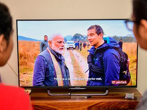 People watch on television the special edition of 'Man Vs Wild' series hosted by survival expert Bear Grylls (R), going on a mission with Indian Prime Minister Narendra Modi, in Bangalore on August 12, 2019.