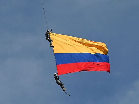 Air Force members Jesus Mosquera and Sebastian Gamboa hang from an helicopter as they wave a Colombian flag as part of a performance during the Flower Festival in Medellin, Colombia