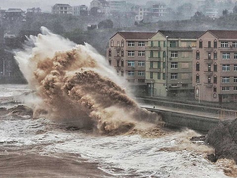 This file photo taken on August 9, 2019 shows waves hitting a sea wall in front of buildings in Taizhou, China's eastern Zhejiang province.