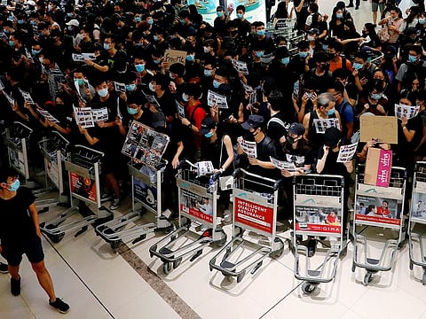 Anti-extradition bill protesters use trolleys to stop passengers from entering the security gates during a mass demonstration after a woman was shot in the eye, at the Hong Kong international airport, in Hong Kong, China. Photo taken on August 13, 2019.