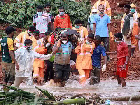 Rescuers carry the body of a victim after extracting it from the debris after a landslide caused by torrential monsoon rains in Kavalappara in Malappuram district, on August 13, 2019.
