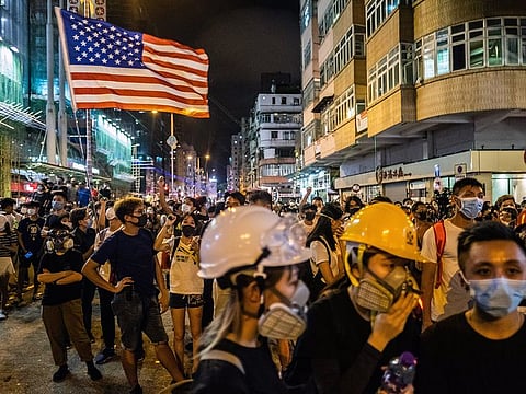 A protestor flies the flag of the U.S. as others train laser pointers on the police station in the Sham Shui Po neighborhood of Hong Kong on Wednesday night, Aug. 14, 2019.