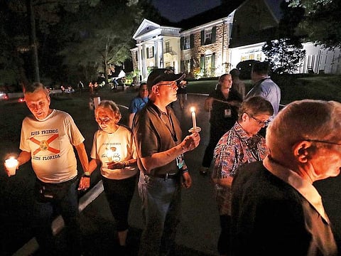 A procession of fans passes by Graceland while visiting Elvis Presley's grave.