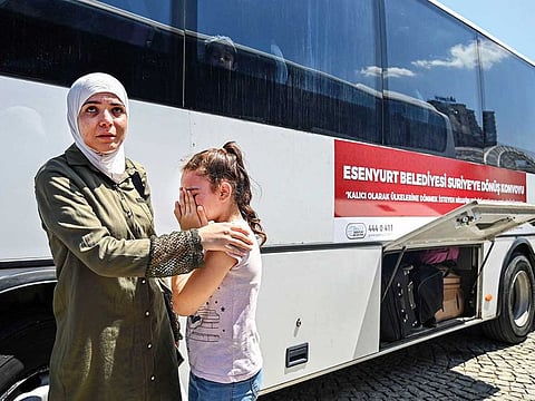 A Syrian girl weeps as families board buses to return to neighbouring Syria in the Esenyurt district of Istanbul earlier this month. Below: More refugee families wait at a bus terminus in the Esenyurt district for their journey back to Syria..