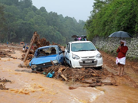 A man stands next to damaged cars after a landslide caused by torrential monsoon rains at Puthumala near Meppadi, Wayanad district, in the southern state of Kerala, India.