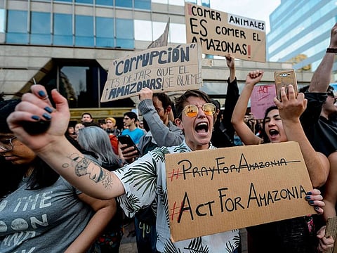 Activists demonstrate during a protest against the government of Brazil's President Jair Bolsonaro over the fires in the Amazon rainforest in front of Brazil's Embassy in Santiago.