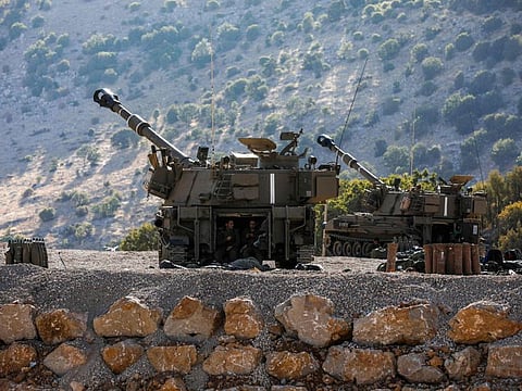 Israeli occupation soldiers sit in the back of a self-propelled artillery gun positioned along the border with Syria in the the Israeli-occupied Golan Heights on August 25, 2019.