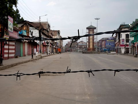 In this Aug. 6, 2019 file photo, a deserted street is seen through a barbwire set up as blockade during curfew in Srinagar.