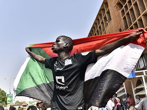 A Sudanese man spreads a national flag in Omdurman as he takes part in a rally in solidarity with Ahmed al-Kheir, a young Sudanese who died in custody after his arrest in January on allegations of organising anti-Bashir protests, on August 28, 2019.
