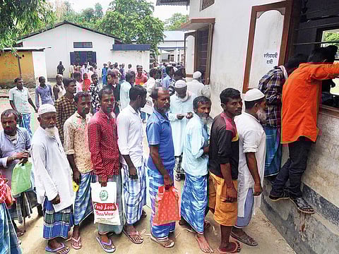 People stand in a queue to check their names on the list of the National Register of Citizens outside a district office in Pavakati village in Assam.