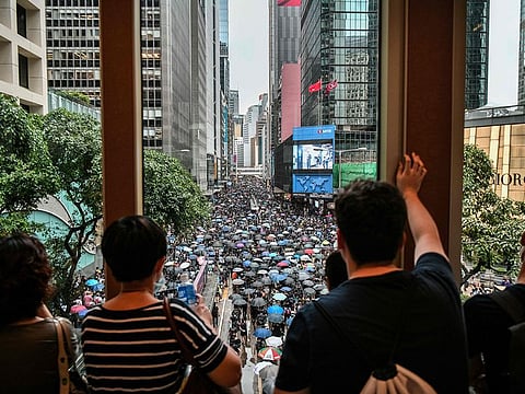 Bystanders watch from a footbridge as protesters march in the Central district of Hong Kong on August 31, 2019.