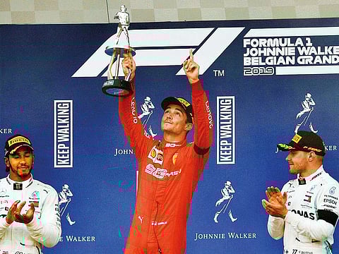 Ferrari’s Charles Leclerc celebrates with a trophy on the podium after winning the race as he applauded by second placed Mercedes’ Lewis Hamilton and third placed Mercedes’ Valtteri Bottas