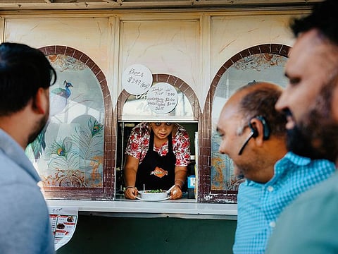 Mansi Tiwari serves food through a window at Punjabi Dhaba, a family-run food truck, in Bakersfield, Calif.